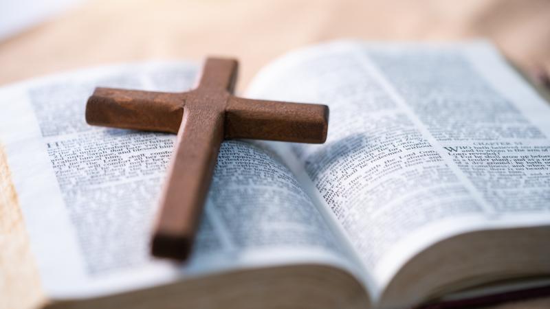 The cross is placed on the Bible.
