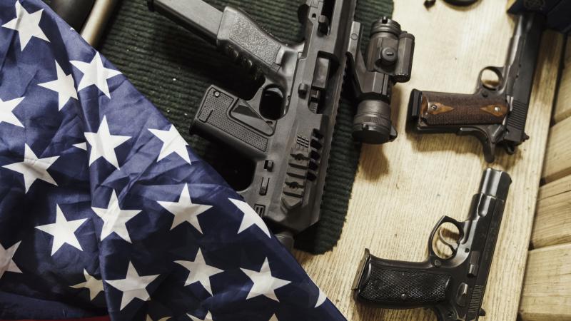 Rifles, guns and American flag on table
